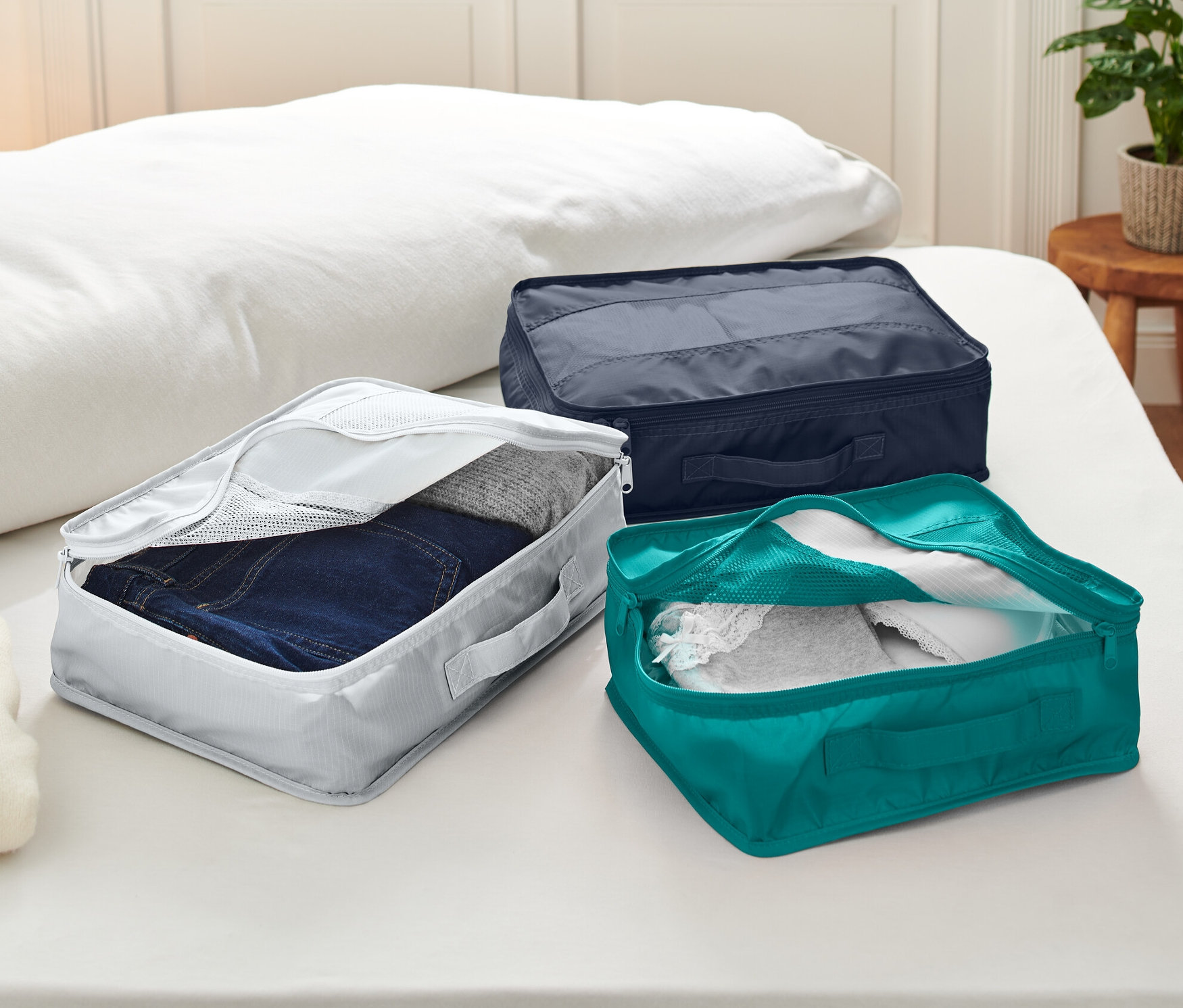 Tri cestovné organizéry ležia na posteli.