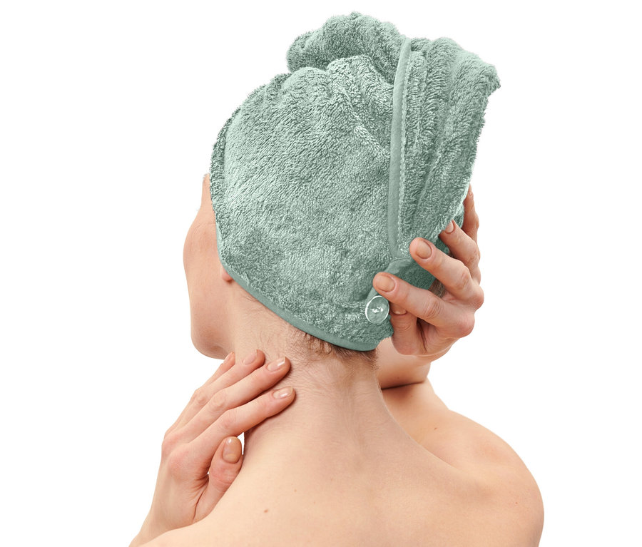 Žena si nasadzuje svetlomodrý uterákový turban.