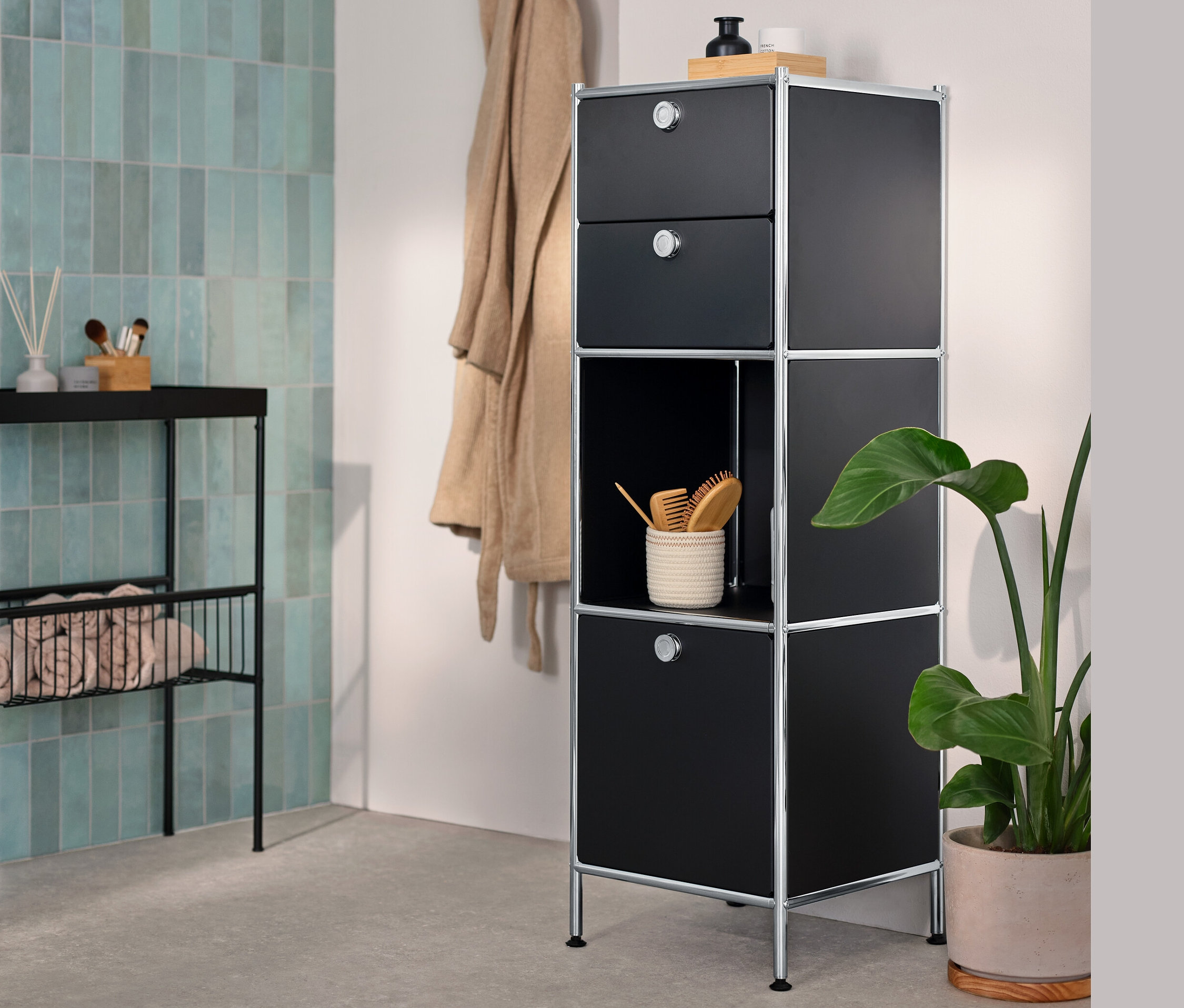 V kúpeľni stojí úzka kovová komoda »CN3« s 2 zásuvkami a 1 výklopným priečinkom a úzka konzola s odkladacími plochami.