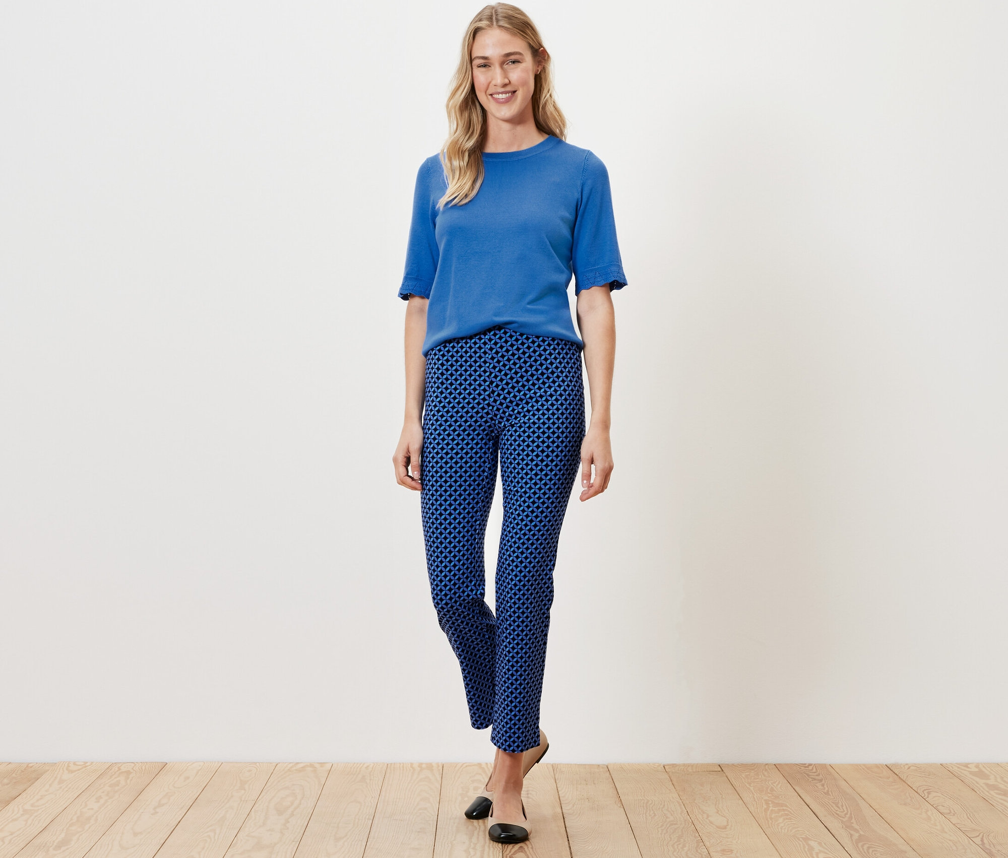 Žena pózuje v kobaltovomodrých elastických nohaviciach s potlačou a modrom tope.