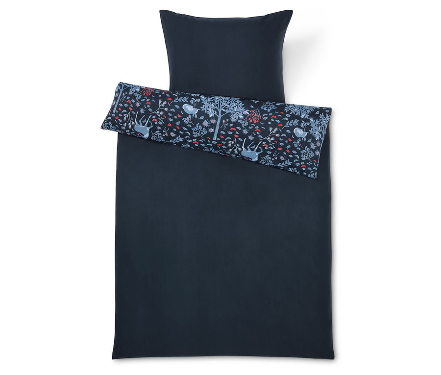 Tmavomodré obliečky s vankúšom a ozdobným vankúšom s potlačou stromov, kvetov a zvierat.