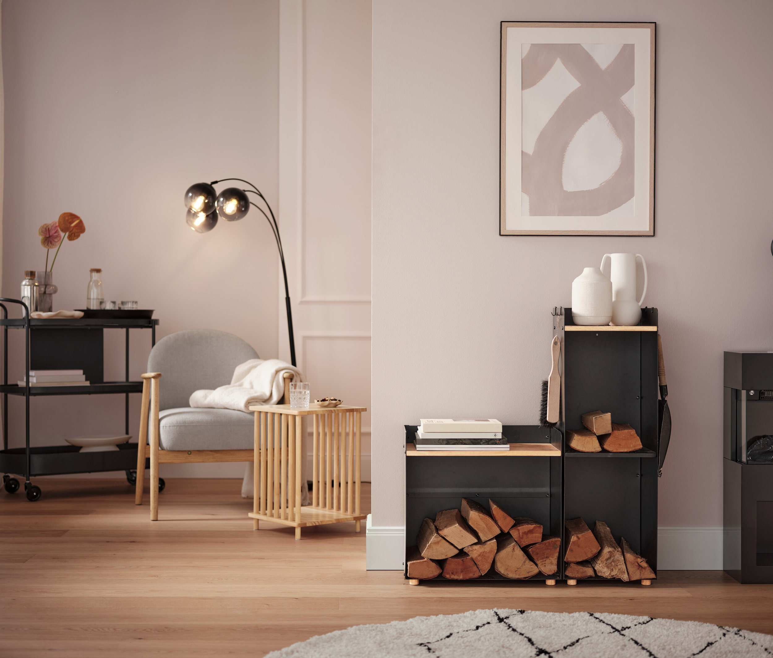 Obývacia izba so sivým kreslom, lampou a vozíkom na kolieskach.