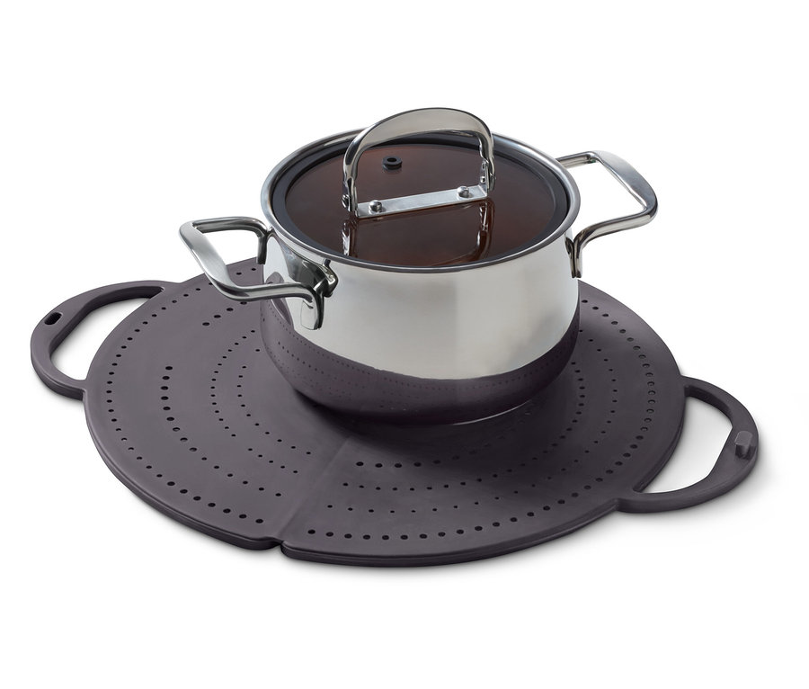 Nerezový hrniec s pokrievkou stojí na fialovej silikónovej podložke s otvormi.