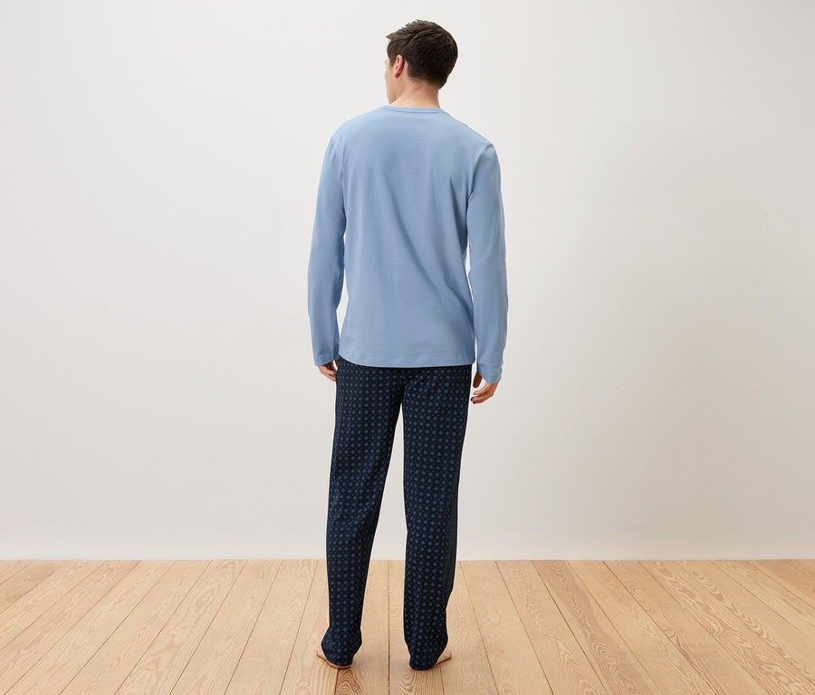 Muž zozadu v svetlomodrom pyžame a tmavomodrých nohaviciach.