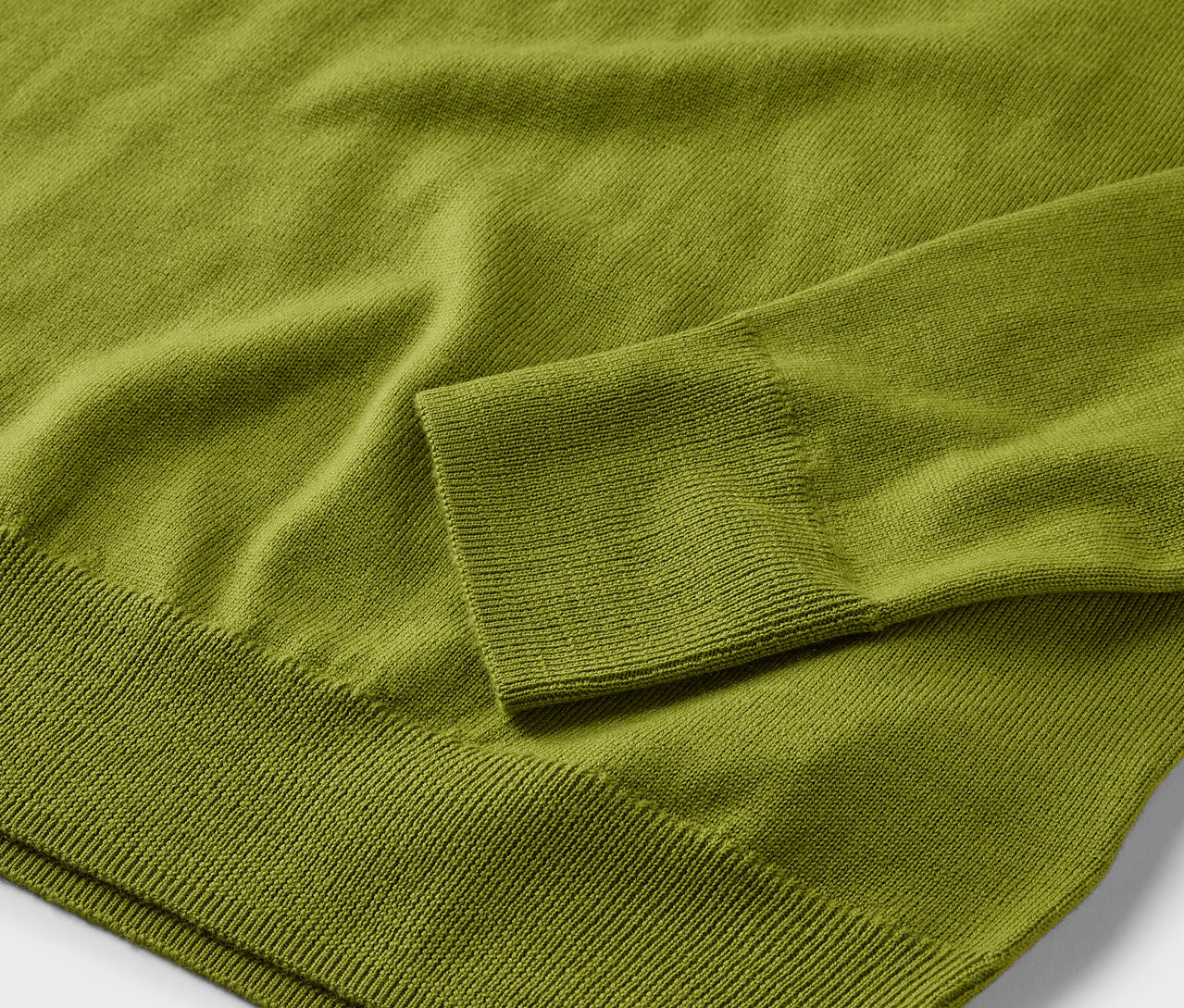 Detail svetlozeleného svetra z merino vlny.