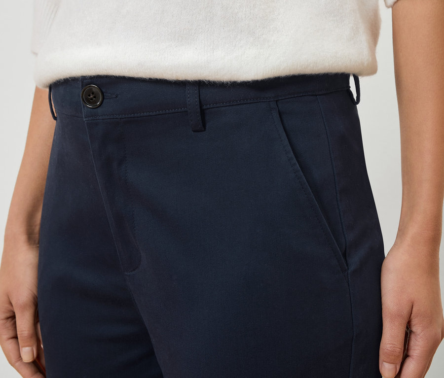 Detailný záber osoby v tmavomodrých nohaviciach a bielom svetri.