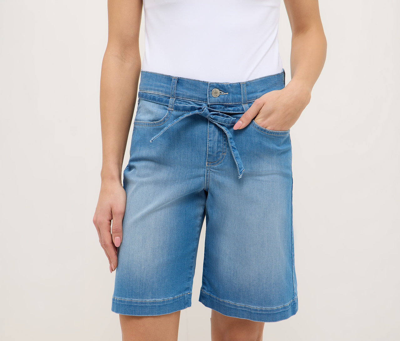 Žena v svetlomodrých šortkách Angels Denim »Lia City« so zaväzovacím opaskom a bielom tope.