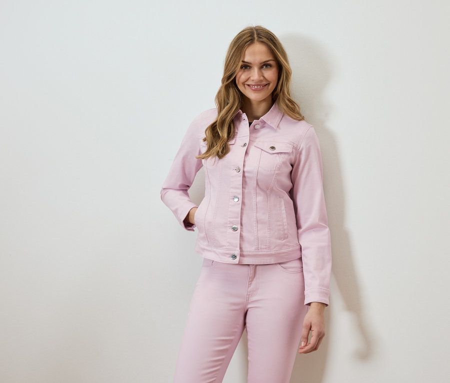 Žena má na sebe ružovú džínsovú bundu a zodpovedajúce džínsy.