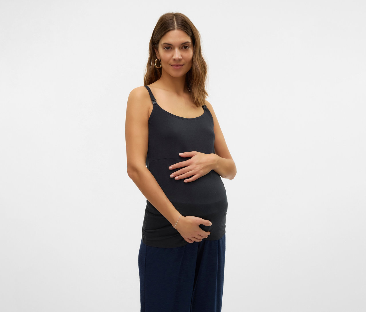 Tehotná žena drží si brucho a má na sebe tielko s tenkými ramienkami MAMALICIOUS v 2-balení »MLKERRIE«.