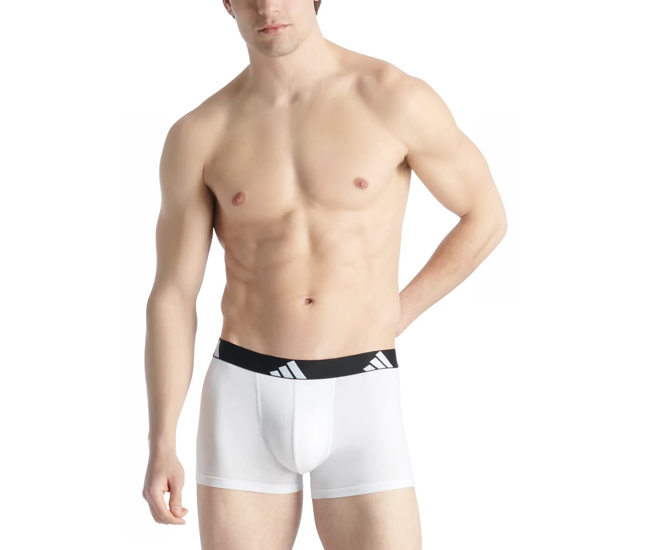 Muž bez trička v bielych boxerkách s čiernym pásom a bielym logom Adidas. Jeho ľavá ruka spočíva na boku.