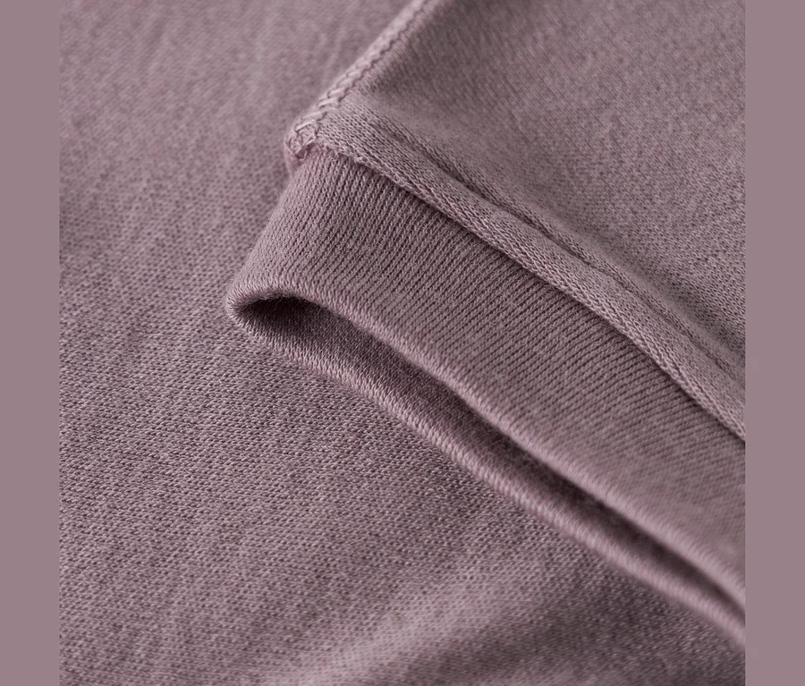 Detail fialovo-sivej látky, zobrazujúci rebrovaný lem a hlavný textil s viditeľným prešívaním.