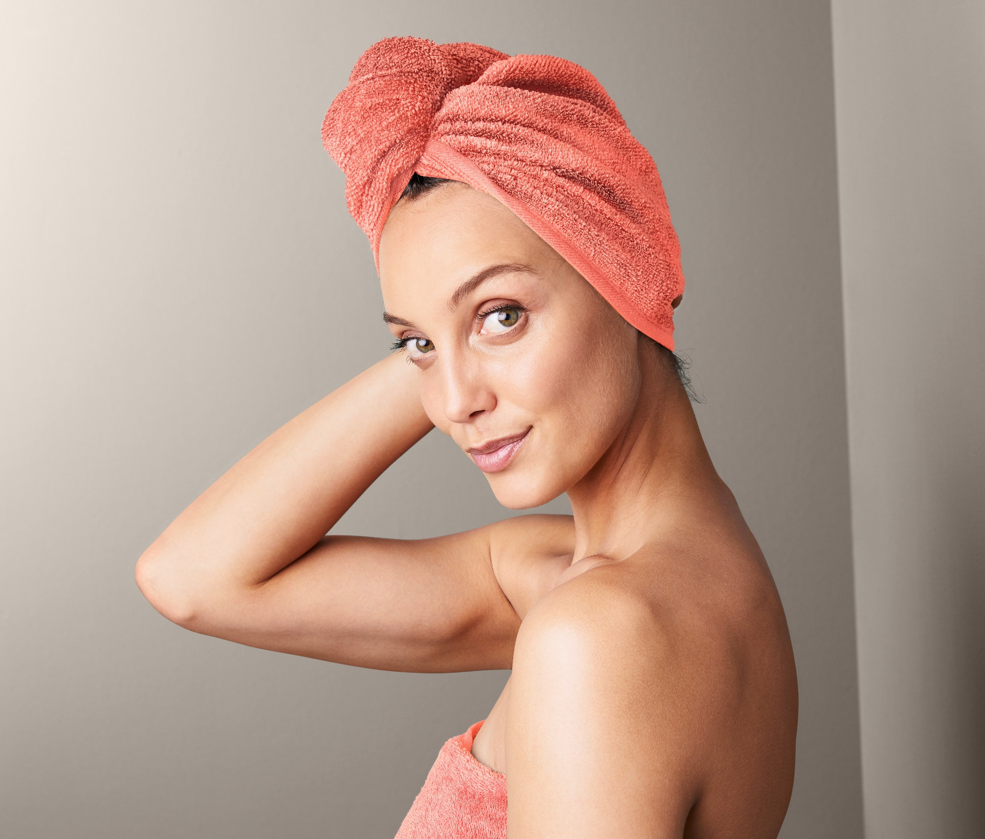 Žena s uterákovým turbanom na hlave a uterákom omotaným okolo tela.