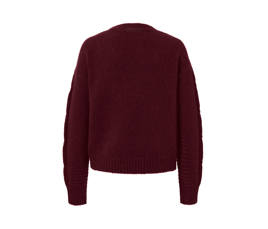 Detailný pohľad na pletený sveter s vrkočovým vzorom.