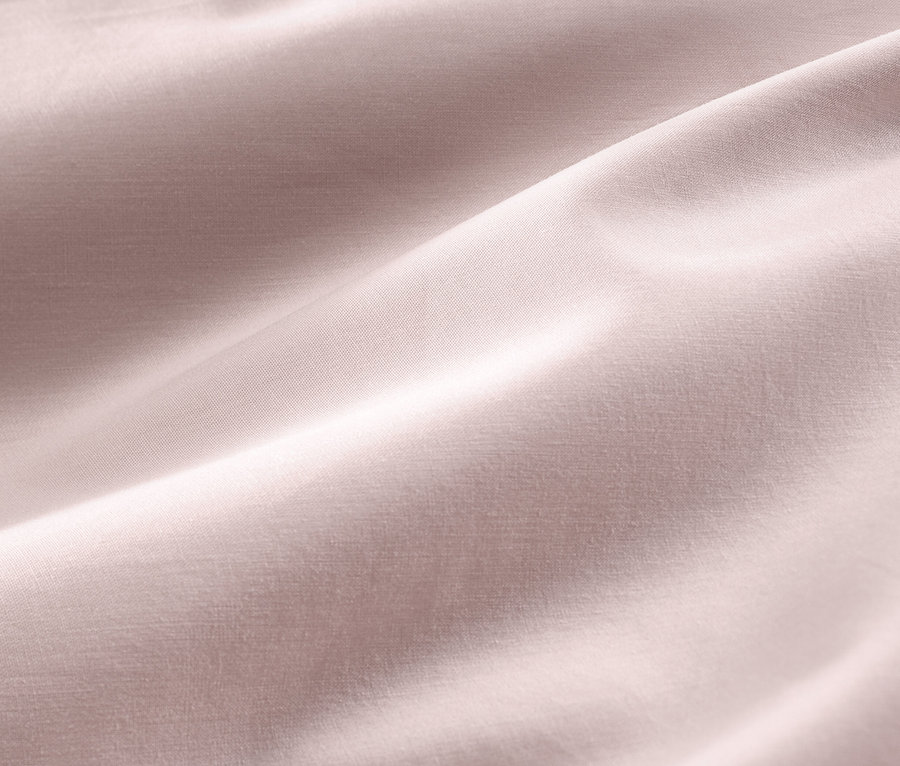 Detailný záber na ružovú bavlnenú saténovú posteľnú bielizeň štandardnej a nadmernej veľkosti.