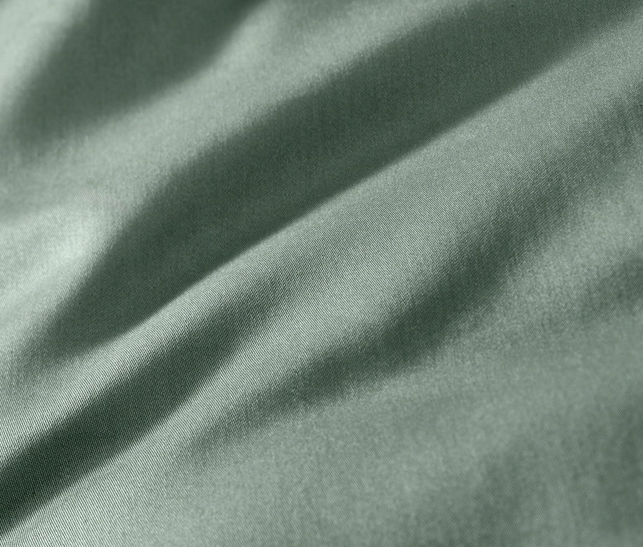 Detailný záber na zelenú bavlnenú saténovú posteľnú bielizeň.