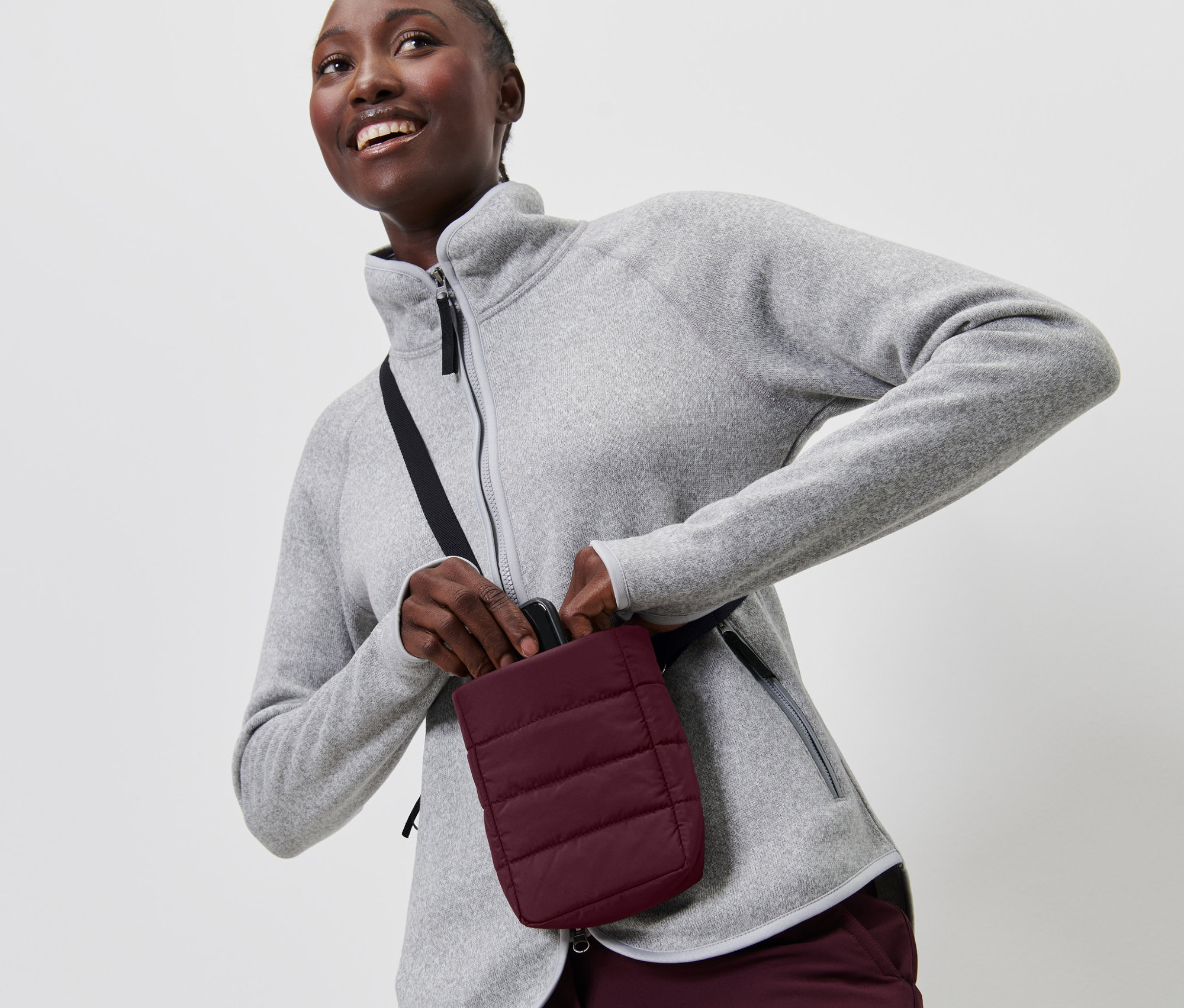 Žena v sivej flísovej bunde vkladá smartfón do puzdra na smartfón s izoláciou.