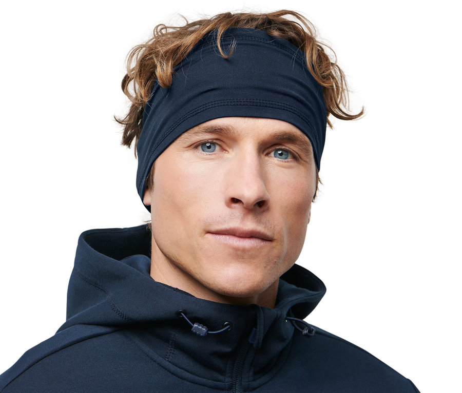 Muž s hnedými vlasmi a modrými očami má na sebe športovú čelenku.