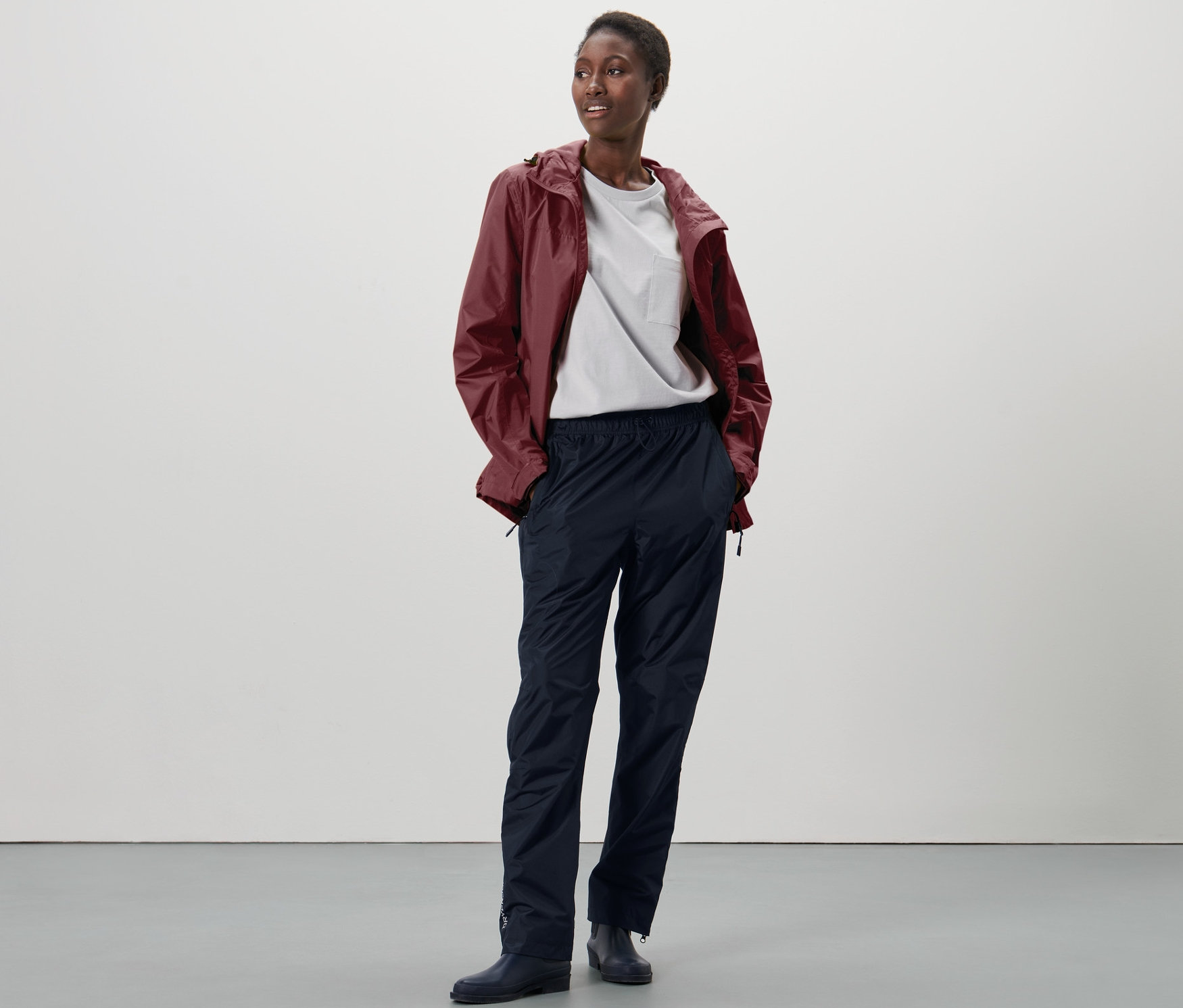 Žena stojí a má na sebe unisexové high-tech nohavice do dažďa.
