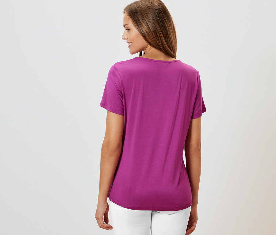 Žena zozadu v tričku so záhybom, bordové a bielych nohaviciach.