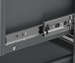 Detail sivého kovového nábytku CN3 so zásuvkou a kovovými koľajnicami.