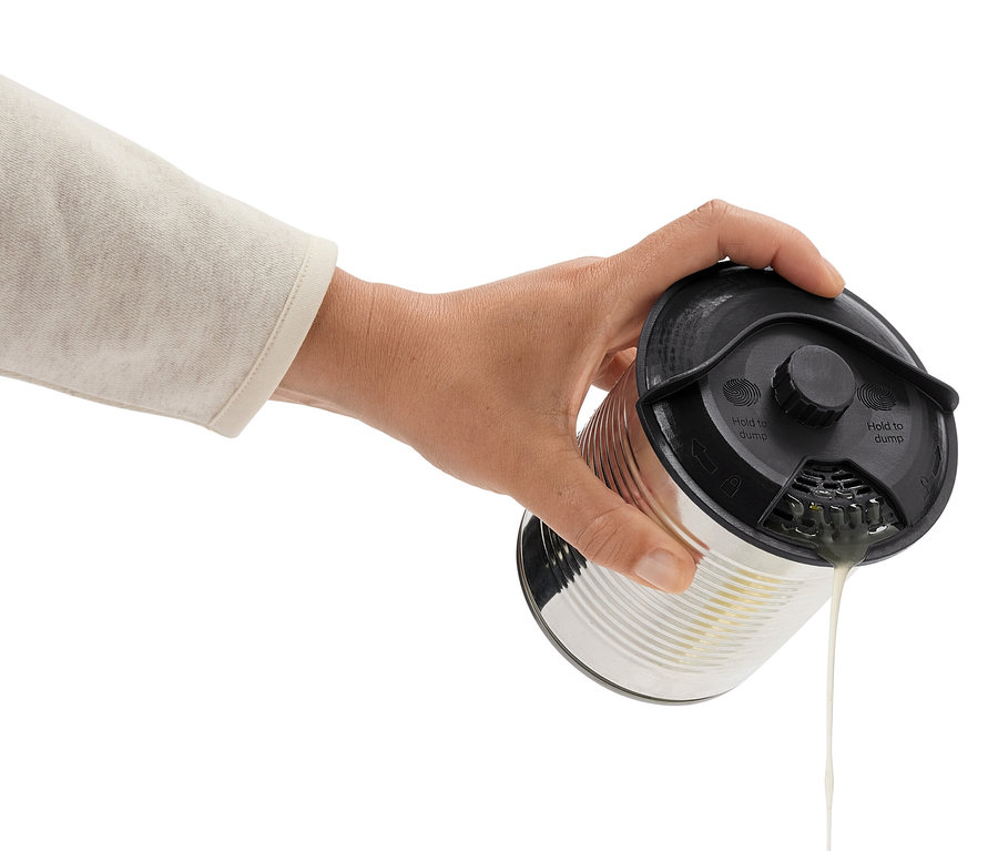 Ruka nakláňa plechovku s čiernym viečkom a vylieva tekutinu.