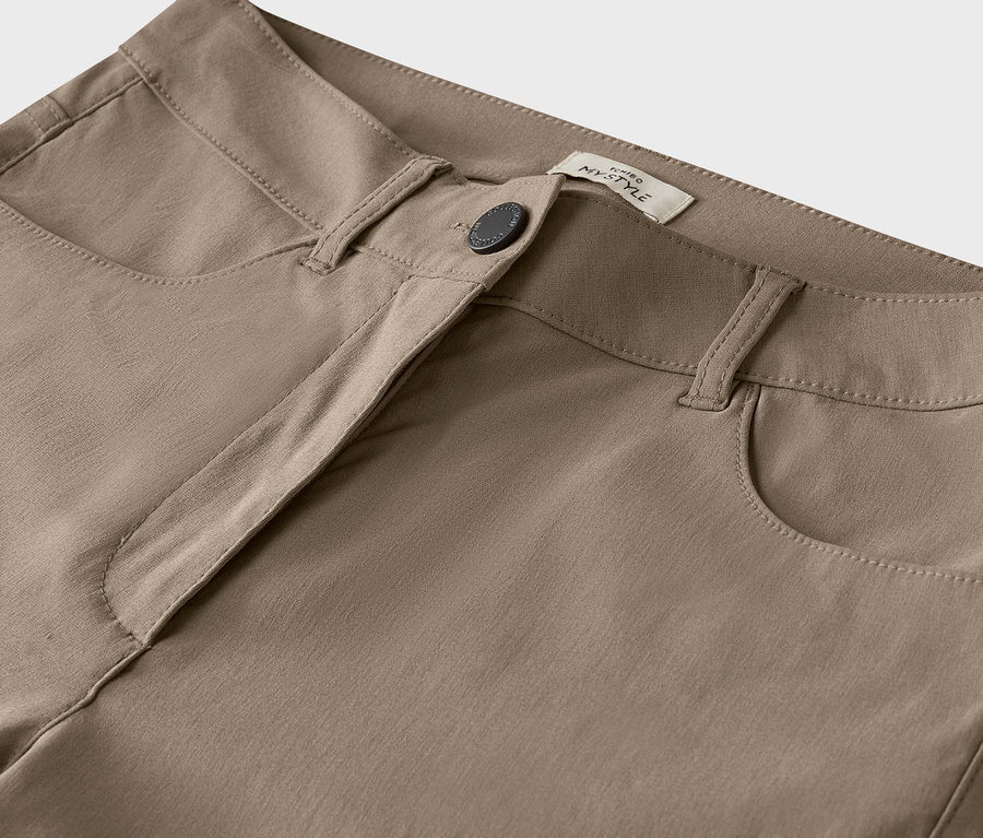 Detail béžových nohavíc s gombíkom.