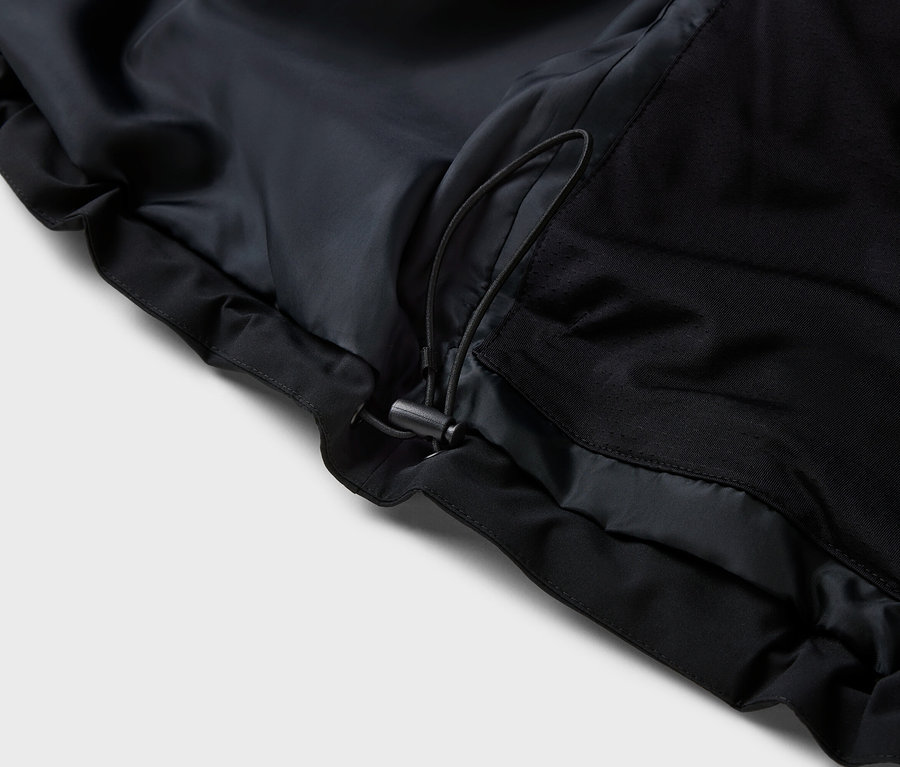 Detail čiernej bundy so sťahovacou šnúrkou.