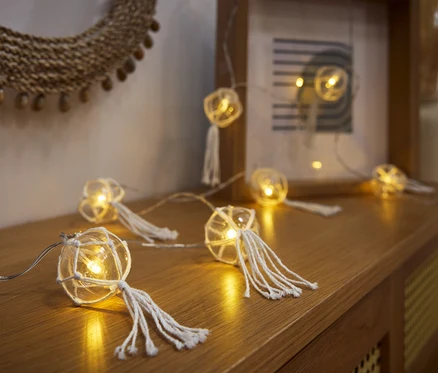 LED svetelná reťaz s guľami leží na drevenej komode.