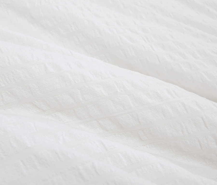 Detailný záber na bielu textúrovanú látku.