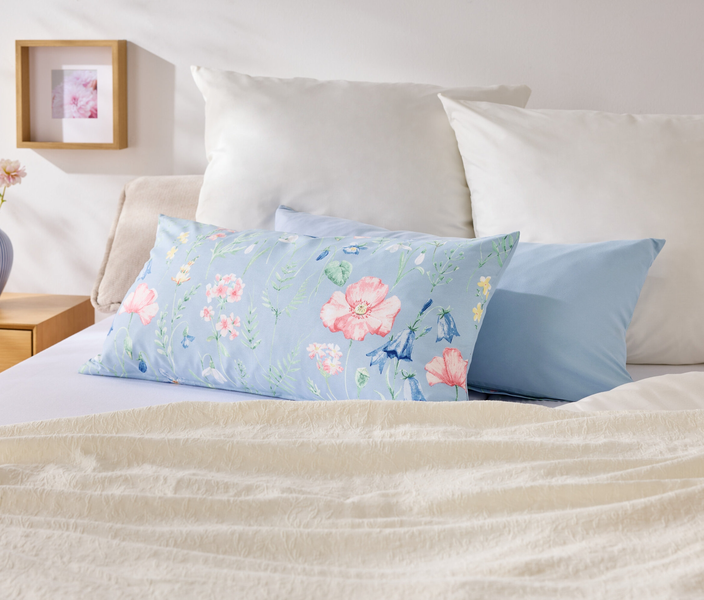 Na posteli sú vankúše rôznych farieb a vzorov.