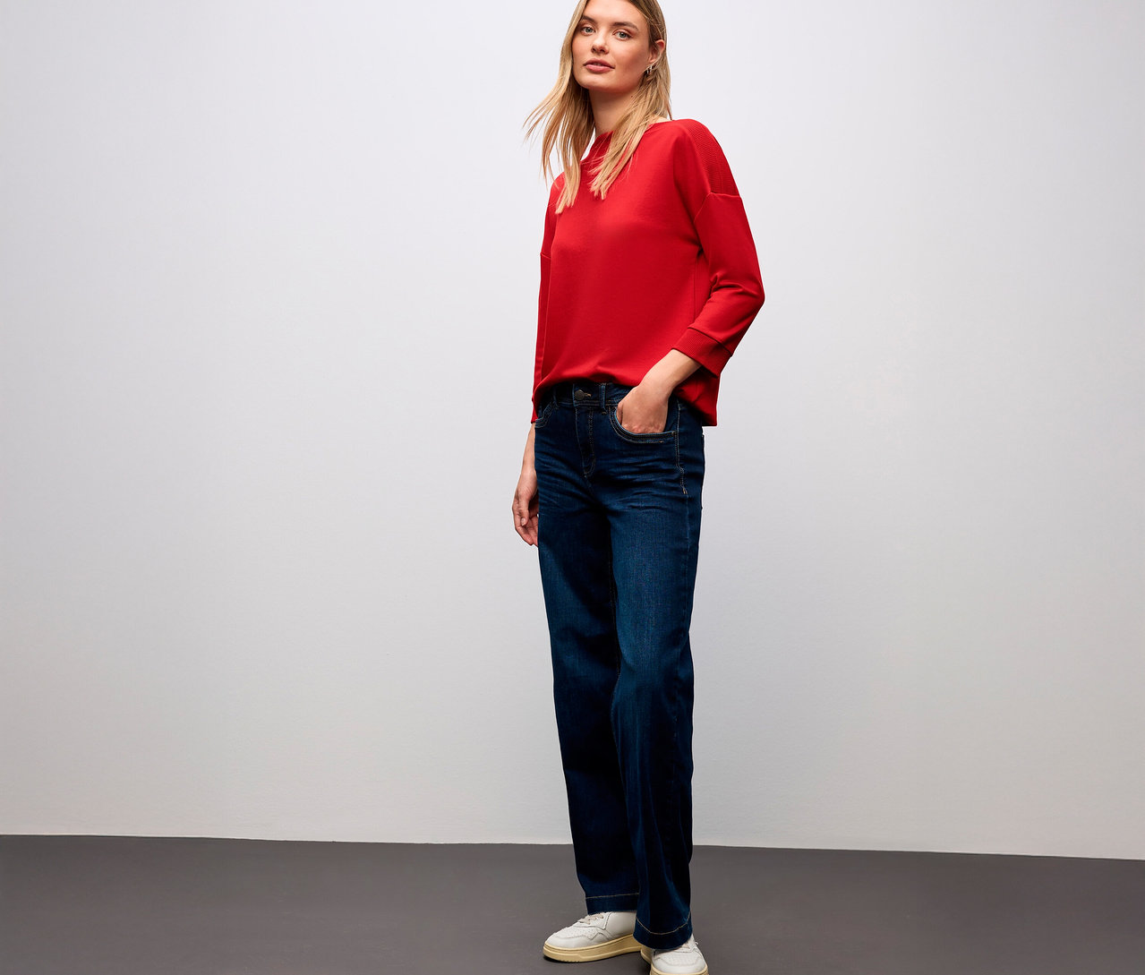 Žena v červenom tričku Street One s rebrovanými detailmi a džínsach.