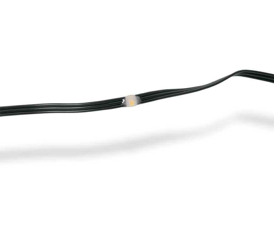 Detailný záber na čiernu svetelnú reťaz s jednou LED žiarovkou, ktorá je priesvitná biela.