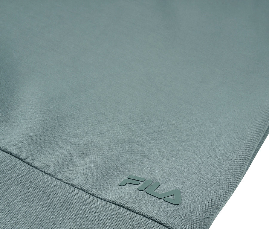 Detailný záber svetlomodrozeleného odevu s logom FILA.