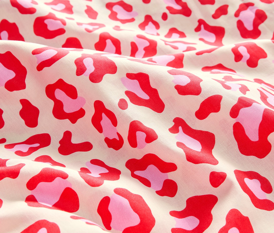 Detail látky s červeným a ružovým leopardím vzorom.