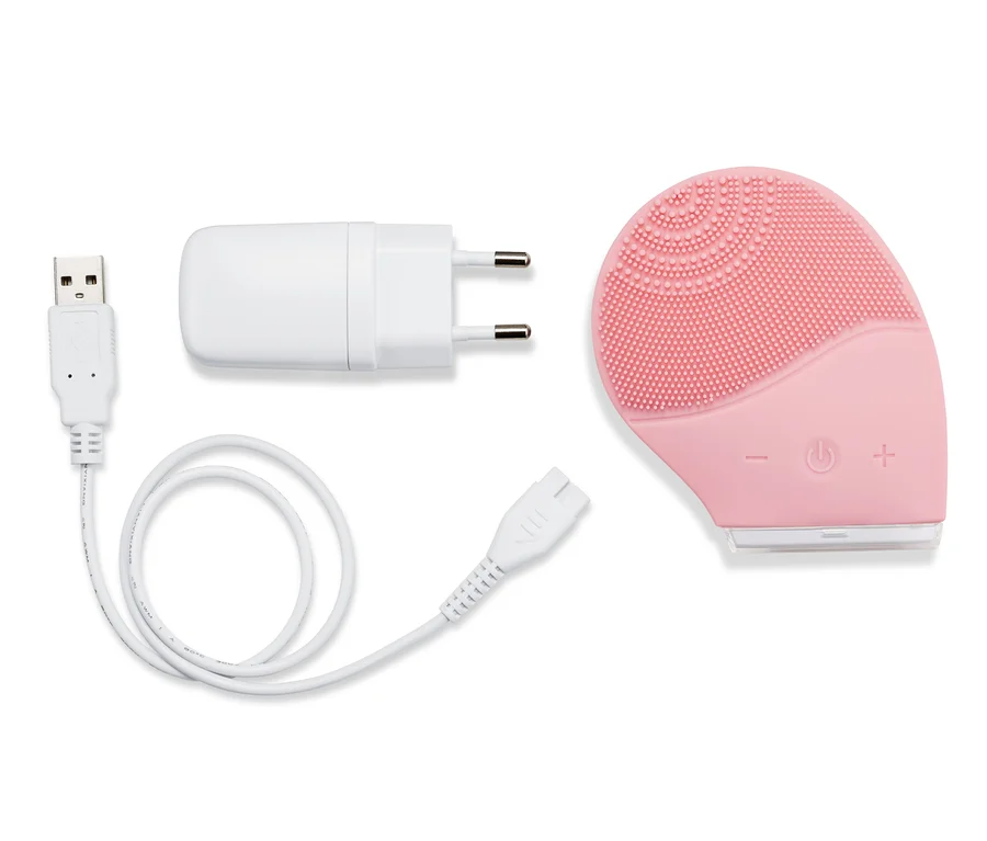 Ružová elektrická silikónová čistiaca kefka na tvár s nabíjacím káblom a adaptérom.