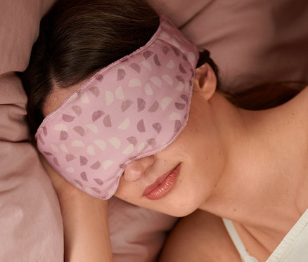 Žena spí v posteli so záťažovou maskou na spanie.