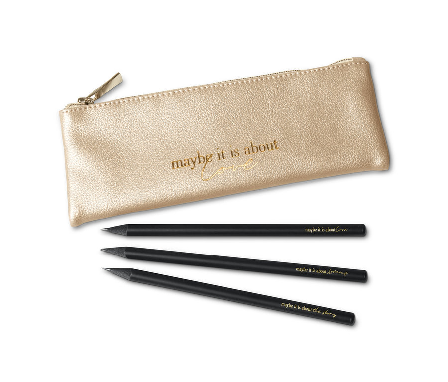 Zlaté puzdro so zipsom leží vedľa troch čiernych ceruziek s nápismi.