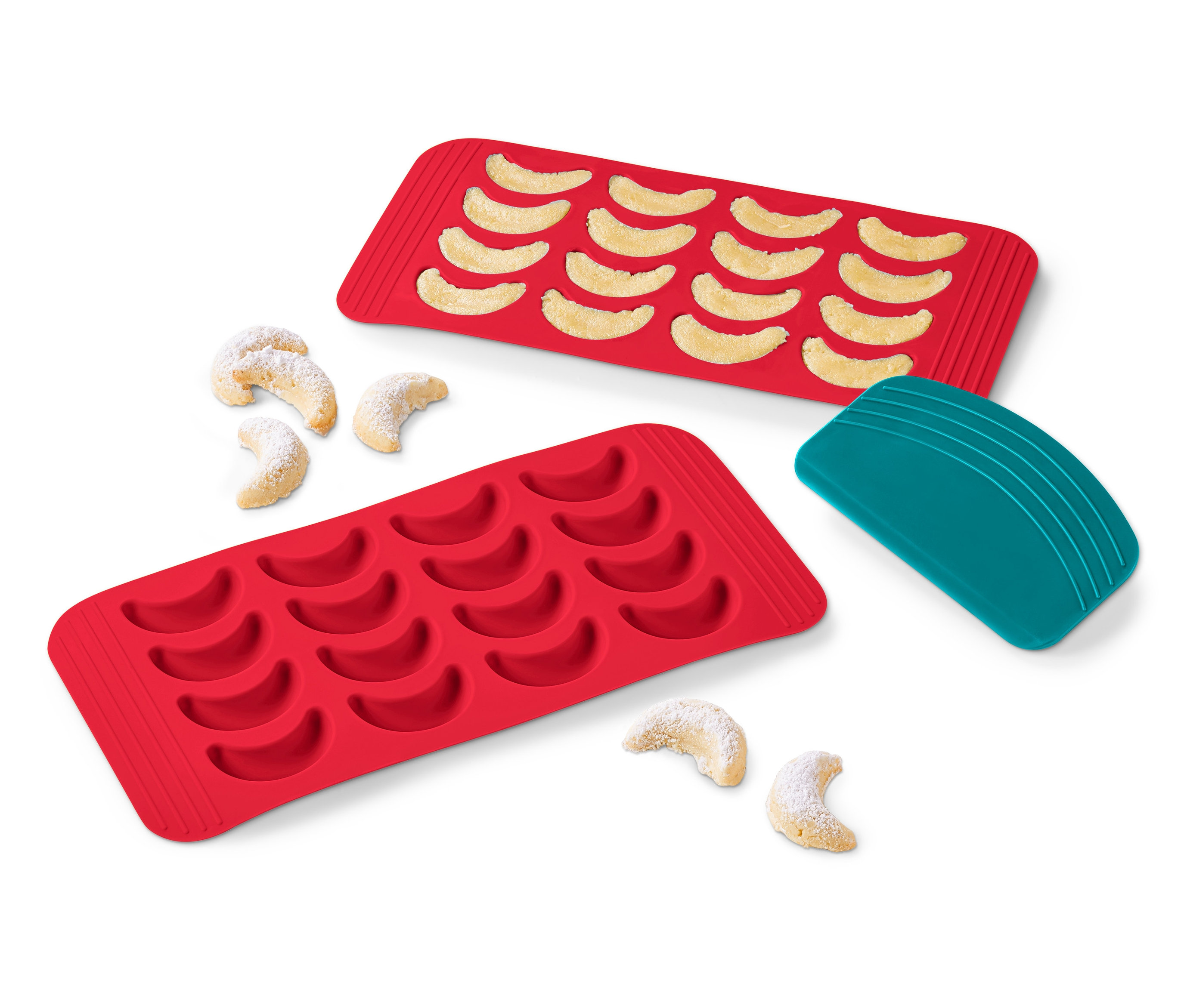 Dve červené silikónové formy na vanilkové rožky, jedna plná upečených rožkov, pár rožkov vedľa formy a tyrkysová škrabka.