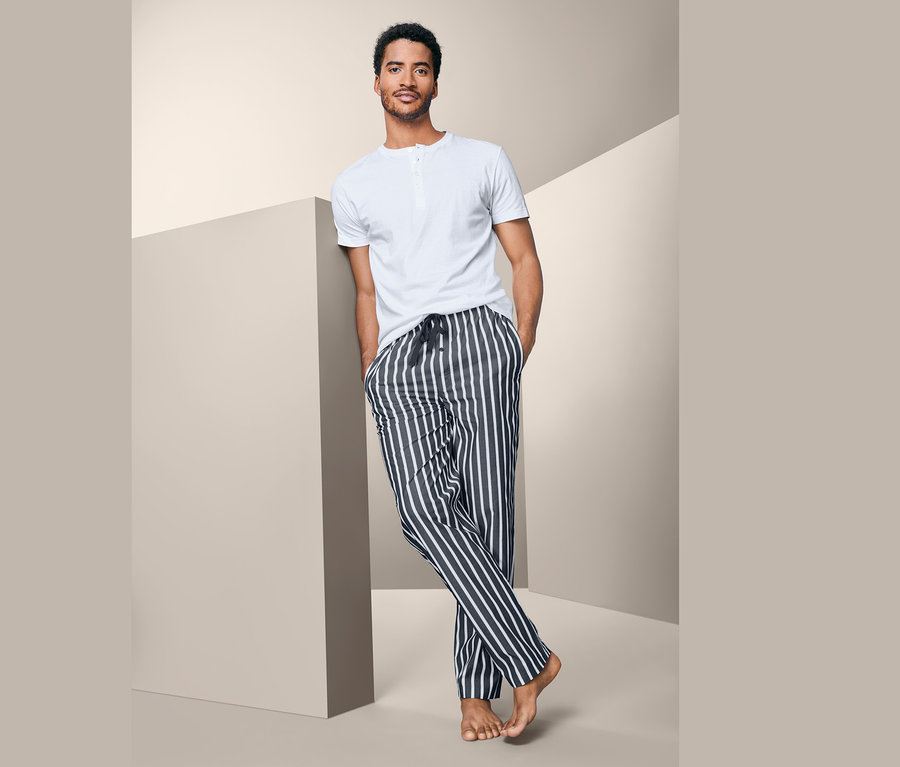 Muž opretý o stenu má na sebe pyžamo.