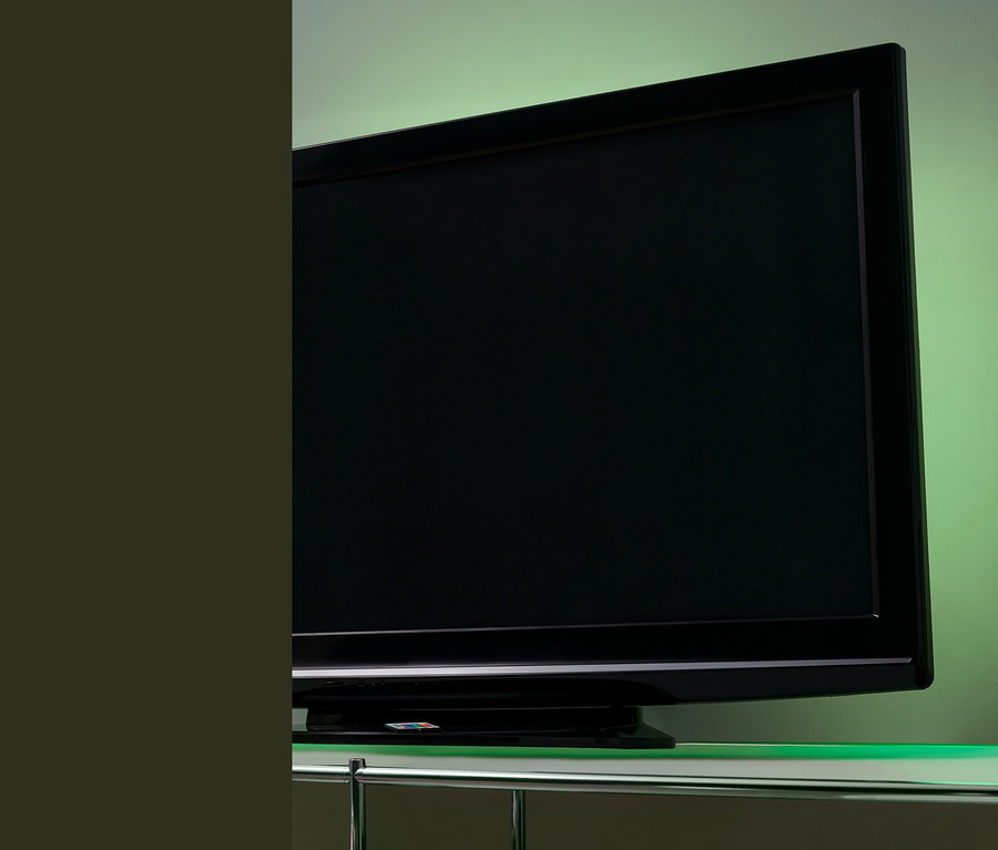 Čierny televízor s podsvietením TV s LED diódami na sklenenom stolíku.