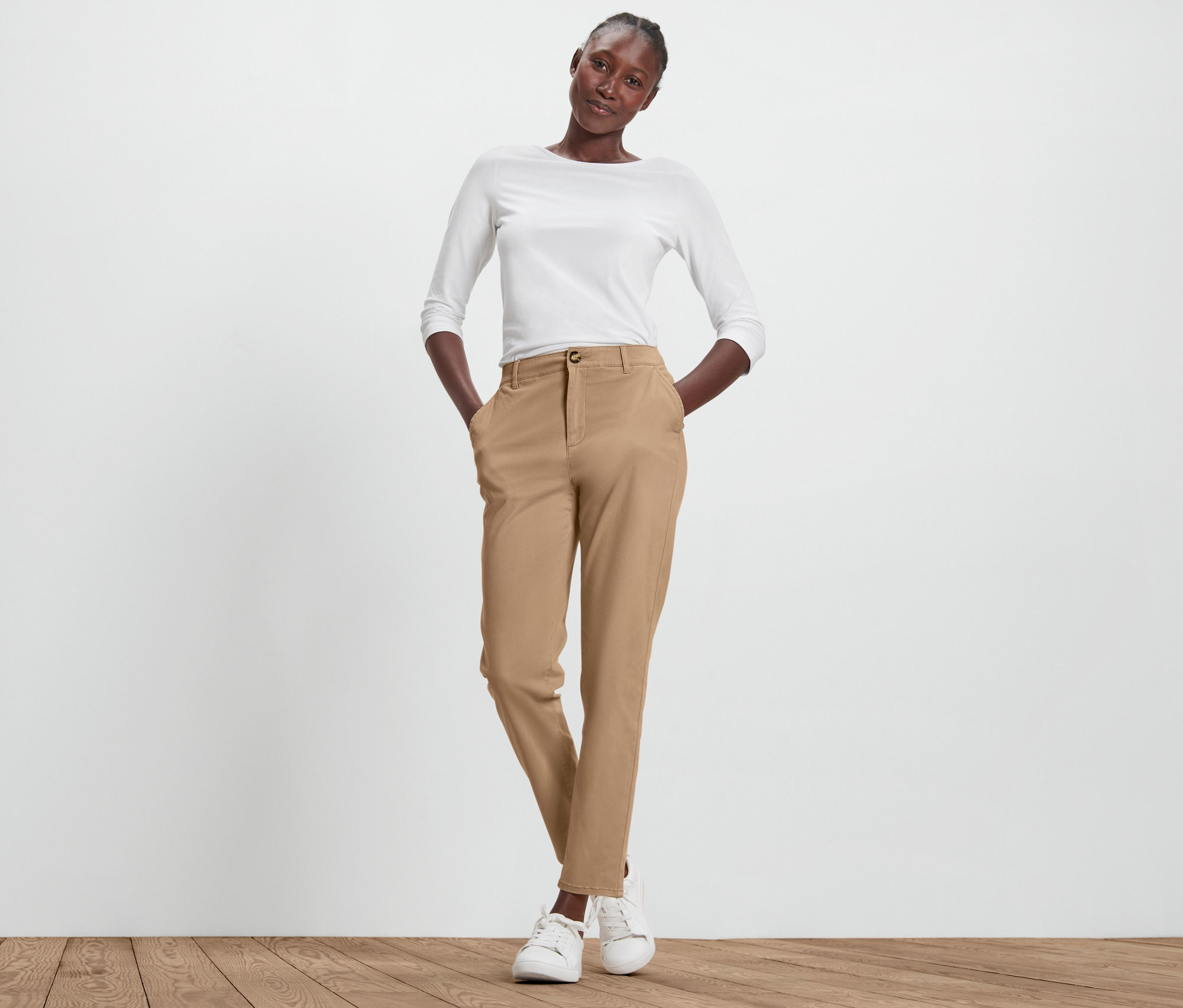 Žena pózuje v béžových chino nohaviciach.