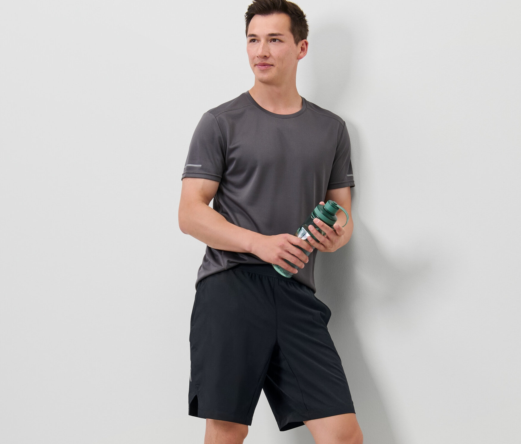 Muž drží fľašu s vodou a má na sebe športové šortky.