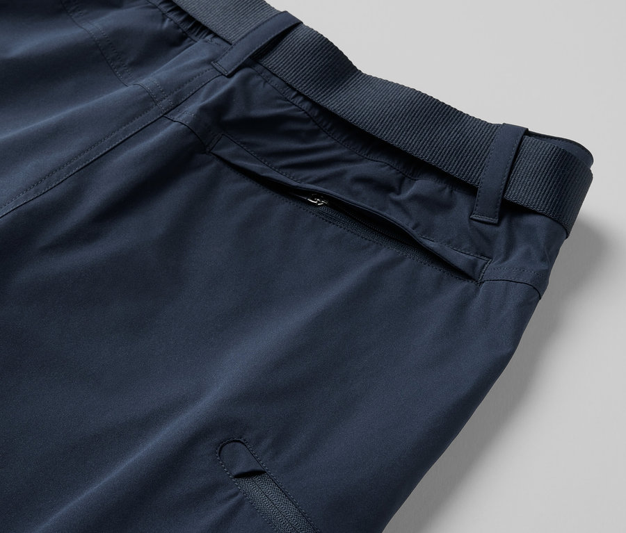 Detail modrých funkčných nohavíc 2 v 1 s vreckami na zips a opaskom.