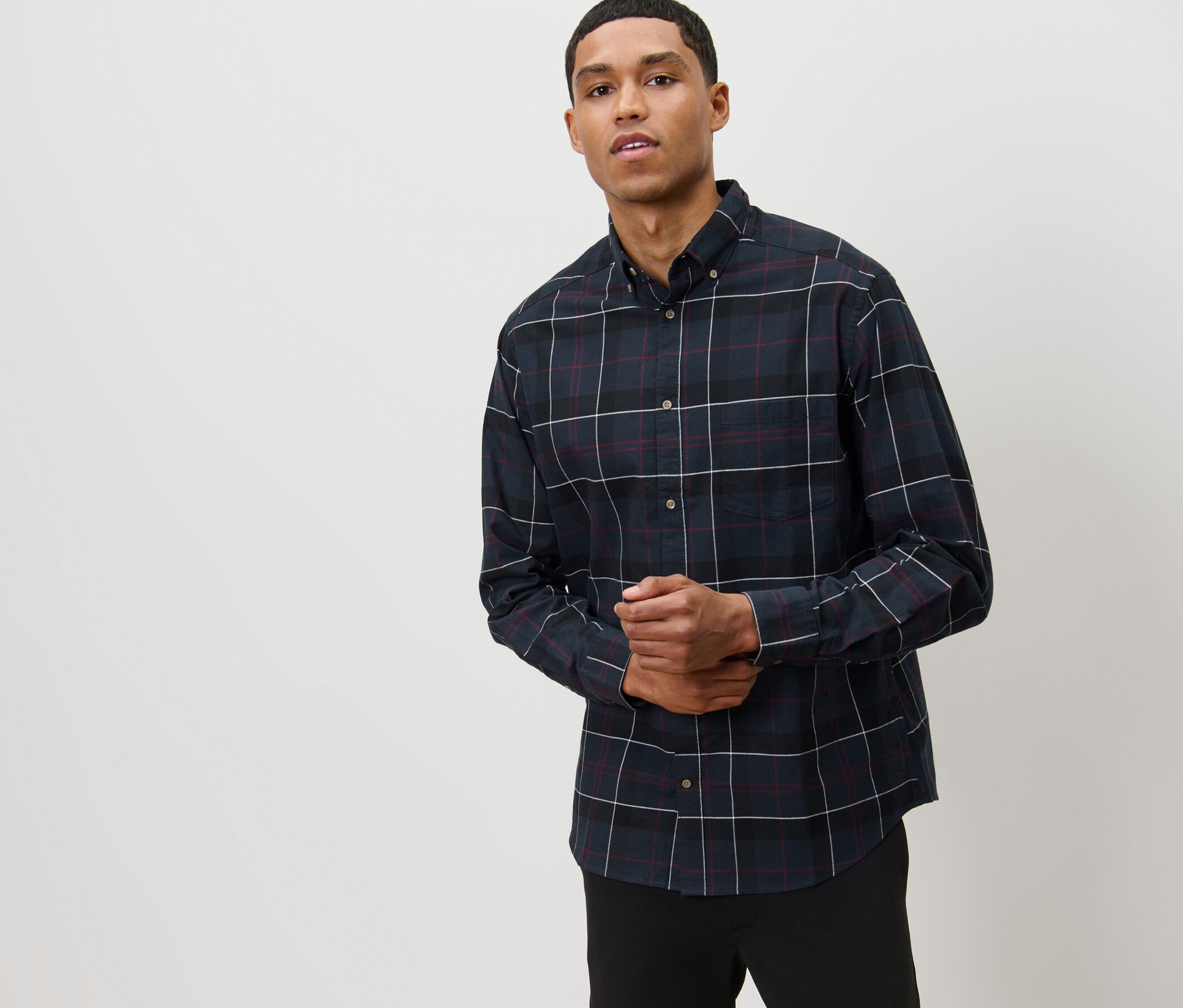 Muž pózuje v tmavomodrej flanelovej košeli.