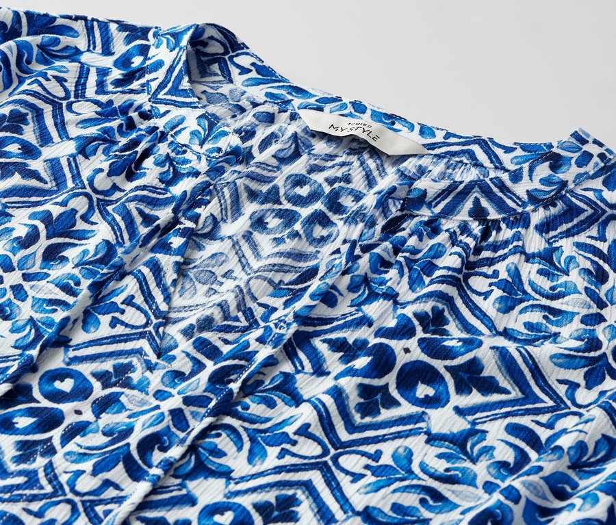 Detail modrej tunikovej blúzky s potlačou.