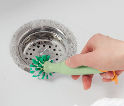 Žena čistí umývadlo univerzálnou čistiacou kefou.