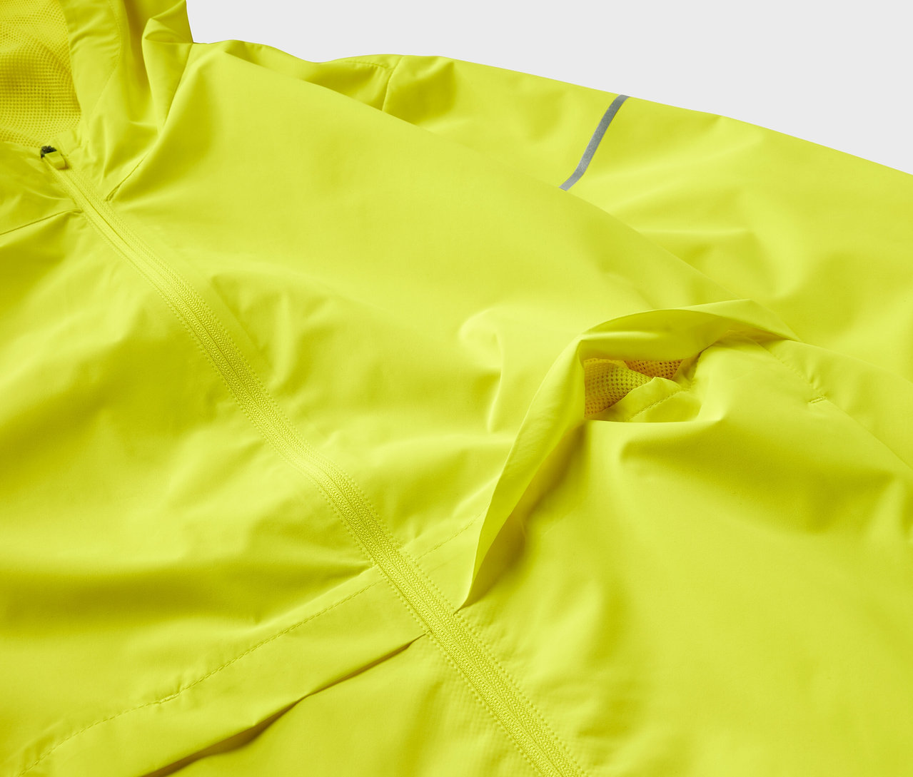 Detail žltej bundy s textúrou a zipsom.