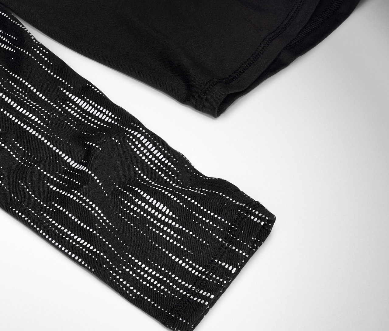 Detail čierneho trička s dlhým rukávom s bielym bodkovaným vzorom na rukáve.