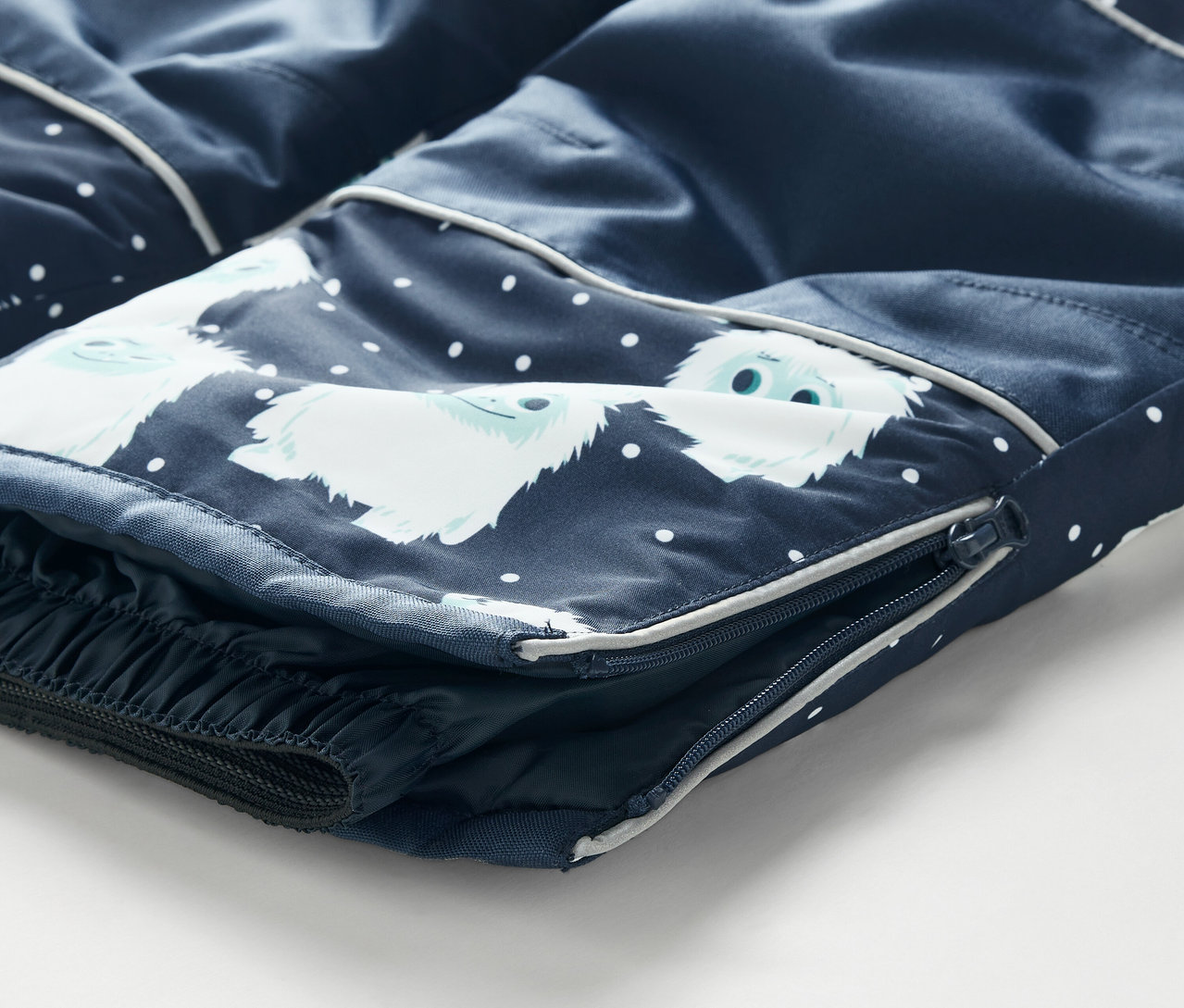 Detailný záber na tmavomodré detské lyžiarske nohavice so zipsom na boku a potlačou bielych snehuliakov.