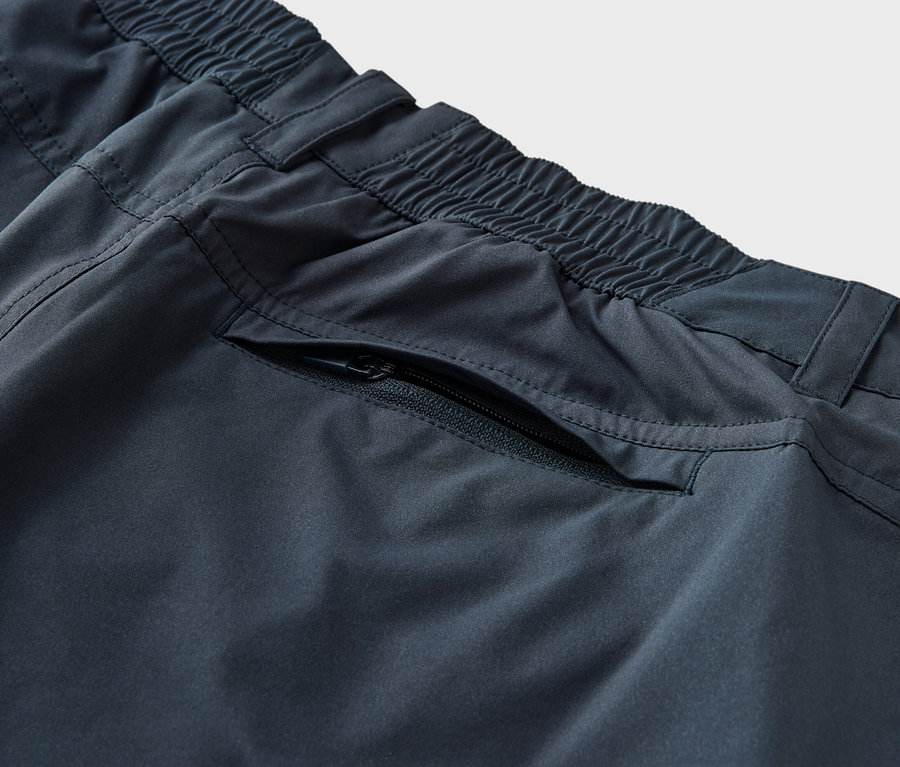 Detail modrých funkčných nohavíc 2 v 1 s elastickým pásom a vreckom na zips.